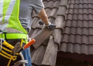 Dachreparatur Dortmund Ein Dachdecker ersetzt einen kaputten Ziegel auf einem Dach
