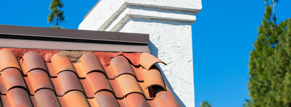 Das Bild zeigt einen Teil eines mit Ziegel gedeckten Daches. Kurz unterhalb des Giebels sind zwei Ziegeln lose und drohen, herunterzufallen. 