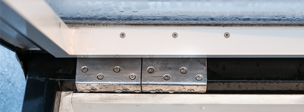 Ein offenes Dachfenster, das an Verbindungsstelen und Schanieren sichtbar undicht ist und Wasser in das Zimmer hineinlässt